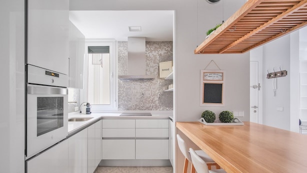 Eine moderne Küche mit weißen Schränken, einem eingebauten Backofen und einer Holz Arbeitsplatte.