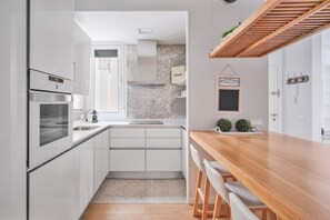A modern kitchen with white cabinets, a built-in oven, and a wooden countertop.