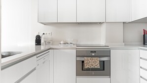 Una cocina moderna con armarios blancos, horno empotrado y lavavajillas.