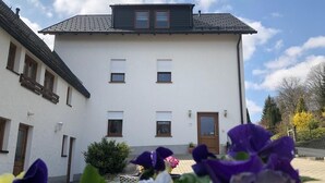 Un edificio a due piani con facciata bianca, diverse finestre e un portone.