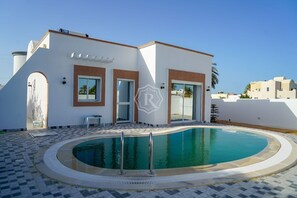 A modern building with a swimming pool, a covered patio, and a view of the surrounding area.
