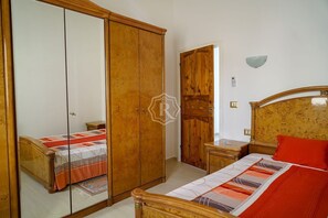 A bedroom with a bed, a wardrobe, a nightstand, and a mirror.