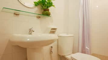 Un baño con lavamanos pedestal, inodoro, cortina de ducha y espejo con una planta en la pared.
