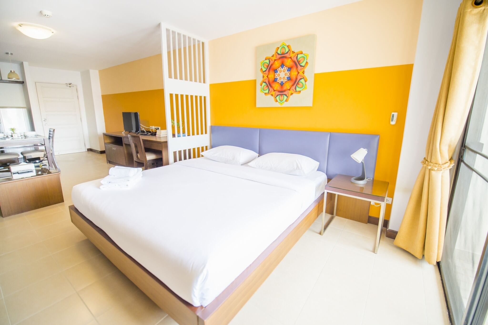 Habitación de hotel con una cama grande, un escritorio con computadora, una silla y un adorno en la pared.