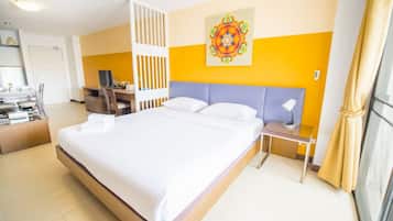 Habitación de hotel con una cama grande, un escritorio con computadora, una silla y un adorno en la pared.