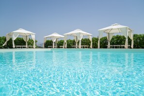 A swimming pool with clear blue water and white canopies providing shade. - Agriturismo Borgo Bernabei (Castiglione della Pescaia)