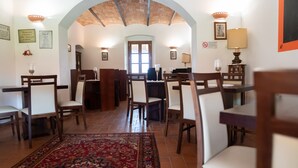 Un espace repas avec des tables et des chaises en bois, un tapis à motifs et un plafond voûté.