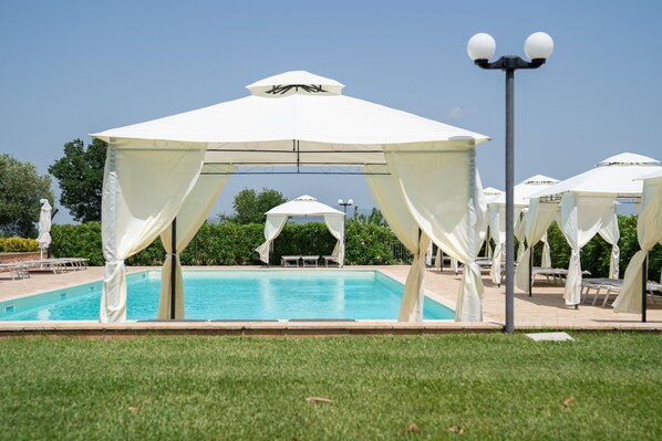 A pool area with white canopies and lounge chairs. - Agriturismo Borgo Bernabei (Castiglione della Pescaia)