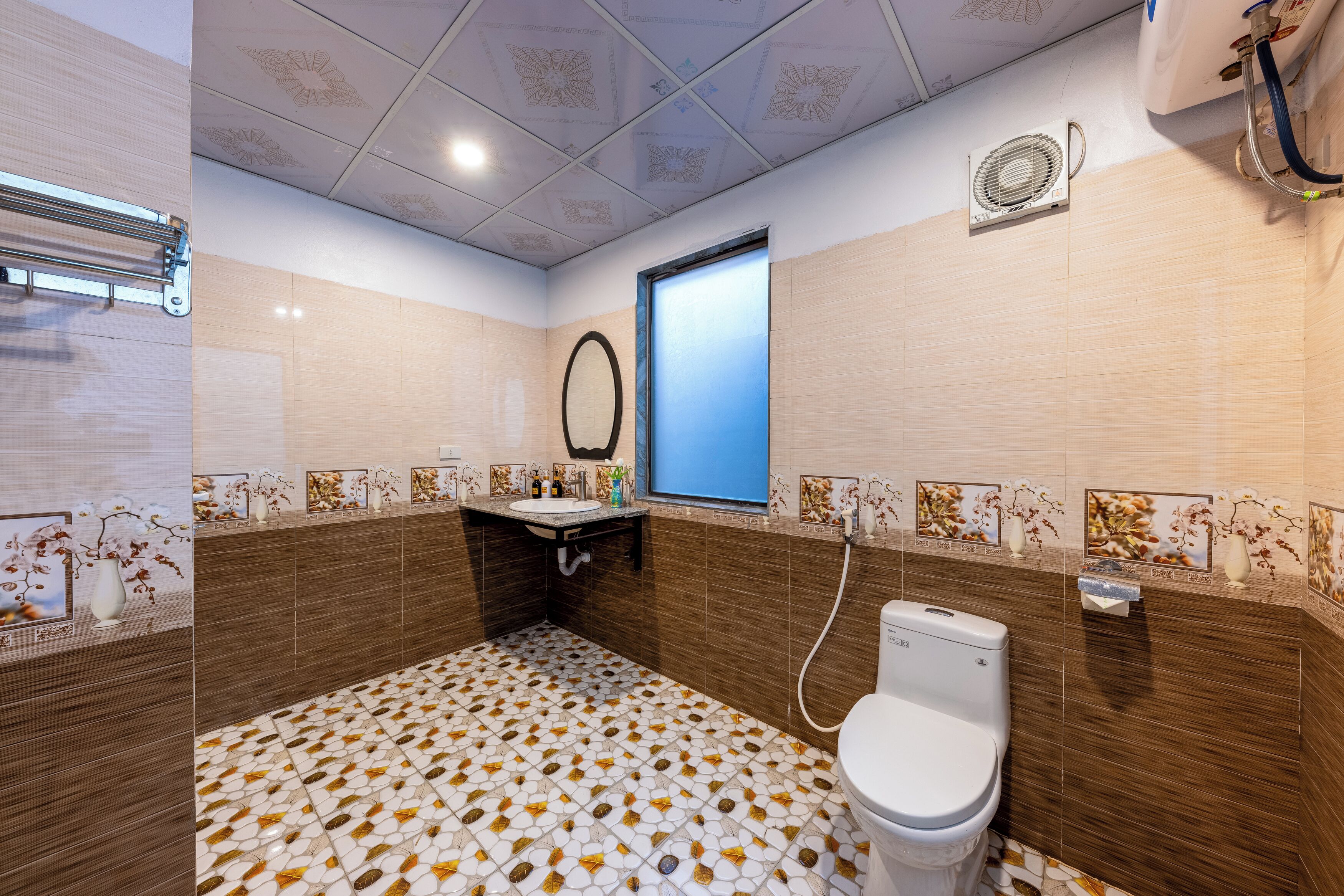 A bathroom with a toilet, sink, mirror, and decorative tiles.