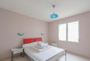 Une chambre à coucher avec un lit, une table de chevet et une fenêtre.
