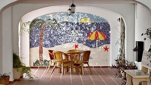 A dining area with a mosaic wall, a table with chairs, and a hanging light fixture.