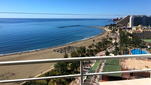 Une vue sur la plage, avec un hôtel, des palmiers et un ciel bleu dégagé.