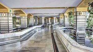 Ein Hotelgang mit Fliesenböden, hängenden Pflanzen und Blick aufs Meer.