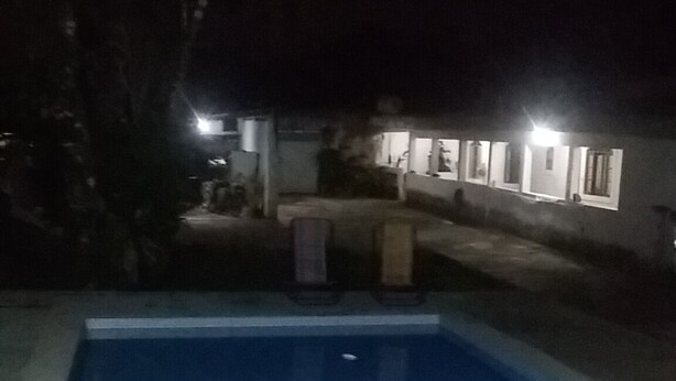 Una piscina con borde de baldosas y una pequeña zona de estar con mesa y sillas.