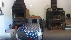 Un comedor con una mesa cubierta por un mantel estampado, dos hornos de ladrillo y una chimenea de ladrillo.