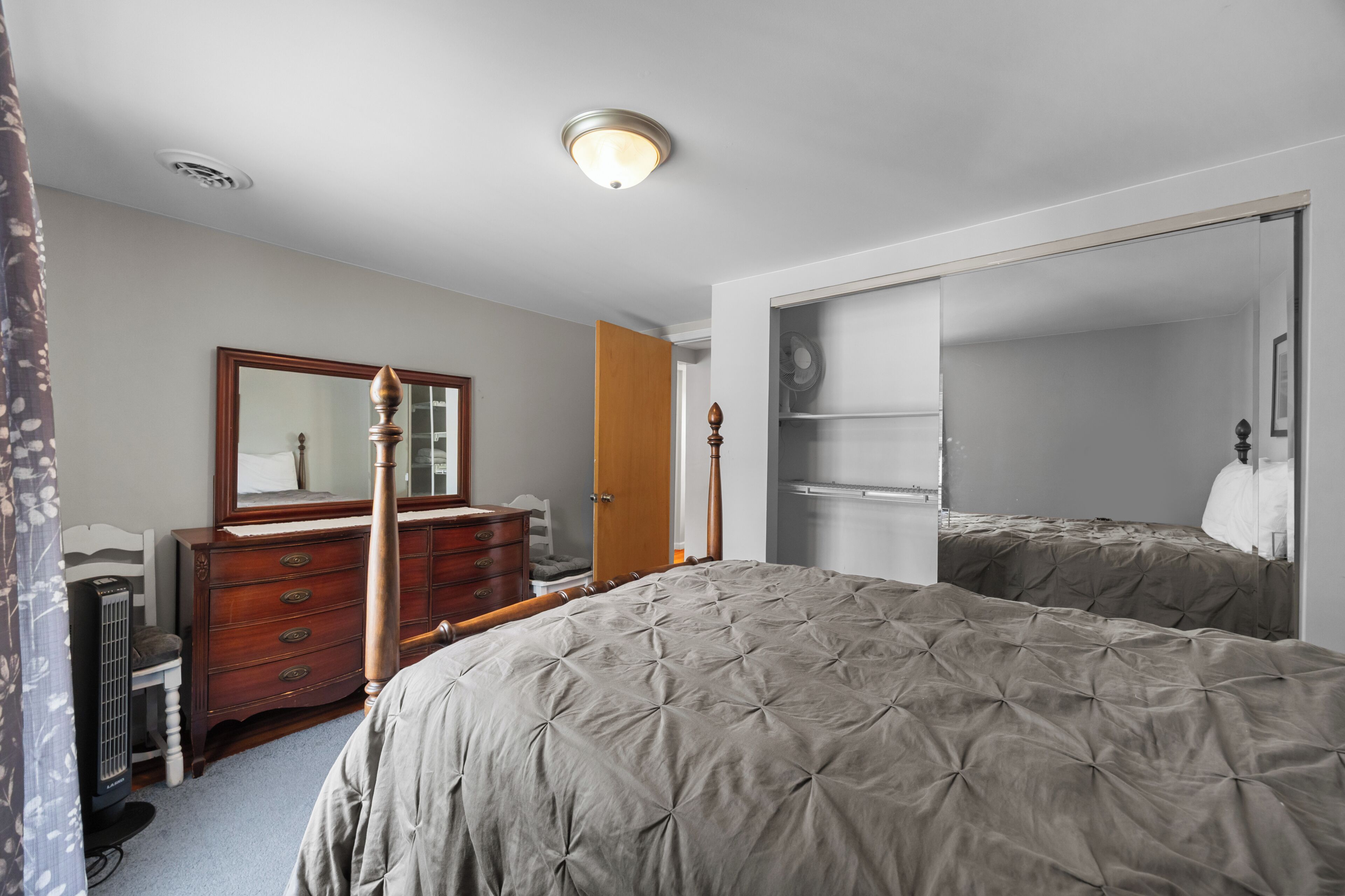 Une chambre à coucher comprenant un lit, une commode, un miroir et une armoire.