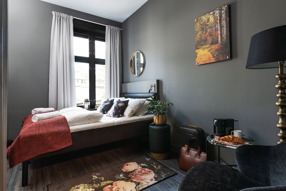 A modern bedroom with a bed, a bedside table, a lamp, and a painting on the wall.