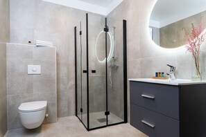 A modern bathroom with a glass-enclosed shower, a toilet, and a vanity with drawers. - Hotel Filip (Oslo)