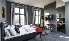 A modern hotel room with a large bed, a desk, a TV, and a view of the city. - Hotel Filip (Oslo)