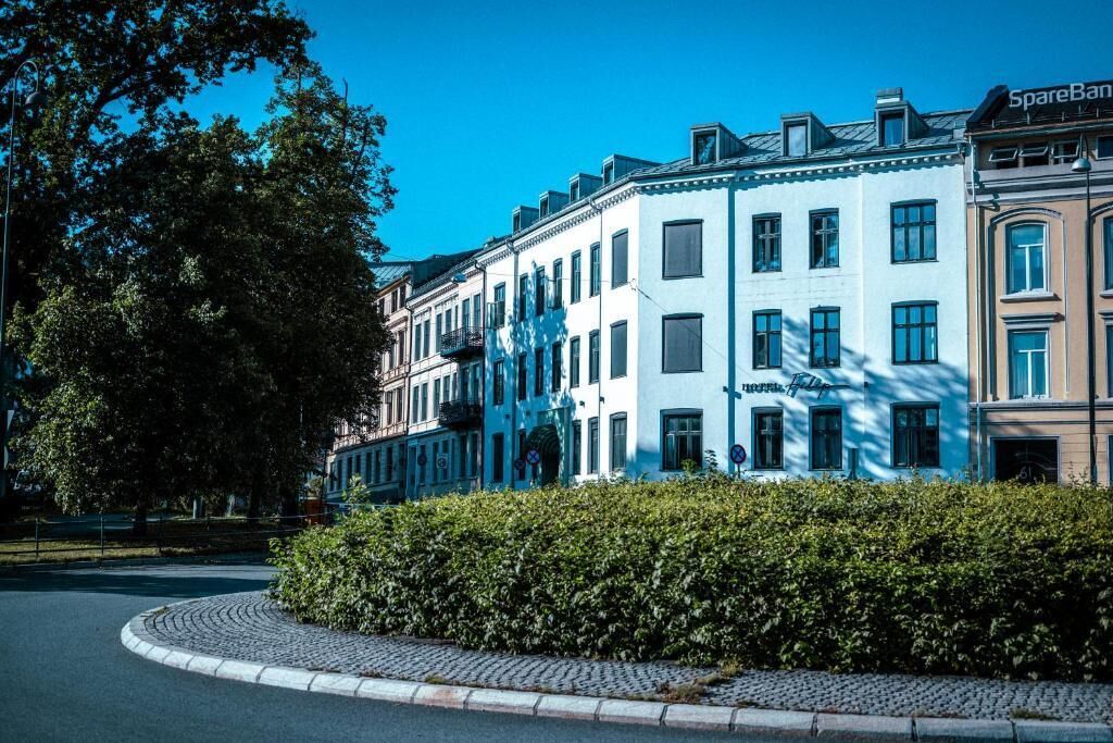Une rangée d’immeubles à plusieurs étages, avec une rue pavée devant.