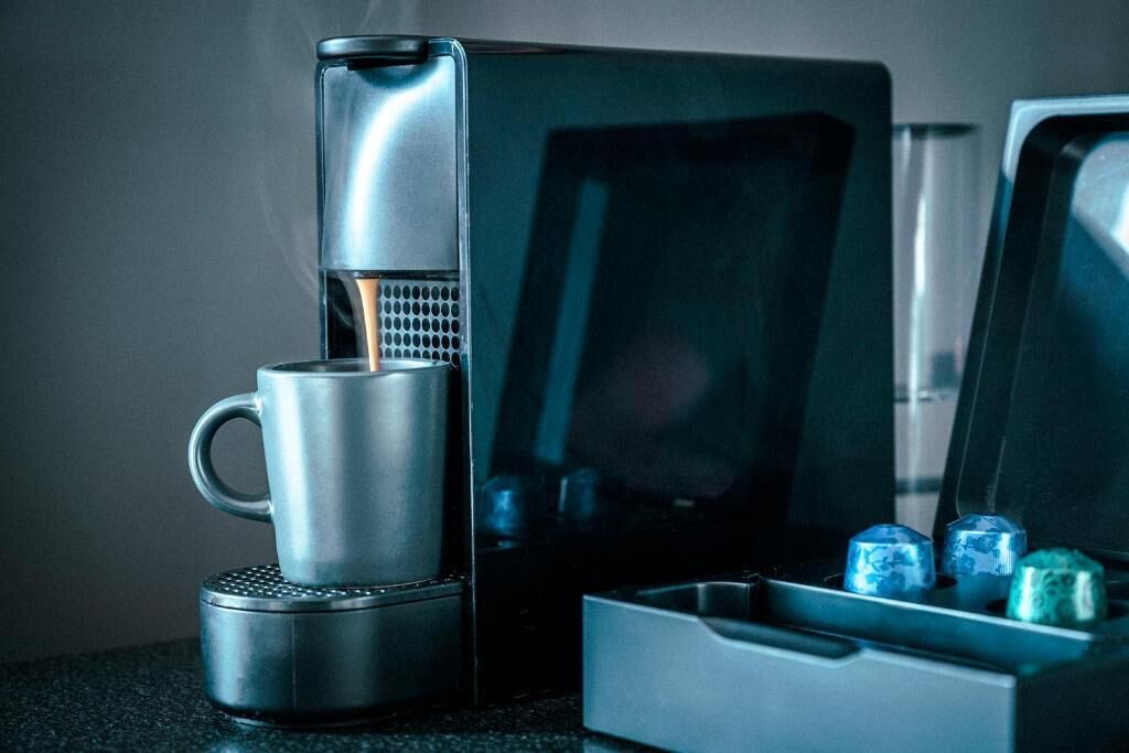 A coffee maker with a cup and a box of ice cubes.