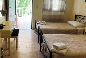 A room with two beds, a desk, and a window.