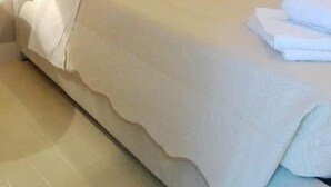 A neatly made bed with a headboard, a lamp on the side, and a painting of a beach on the wall. - Anemologio Studios (Kefalonia)