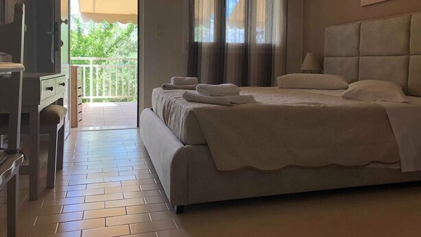 A bedroom with a bed, a TV, and a balcony. - Anemologio Studios (Kefalonia)