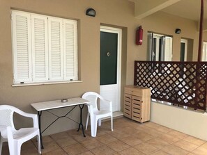 A small room with a table and two chairs, a wooden cabinet, a green door, and a fire extinguisher on the wall.
