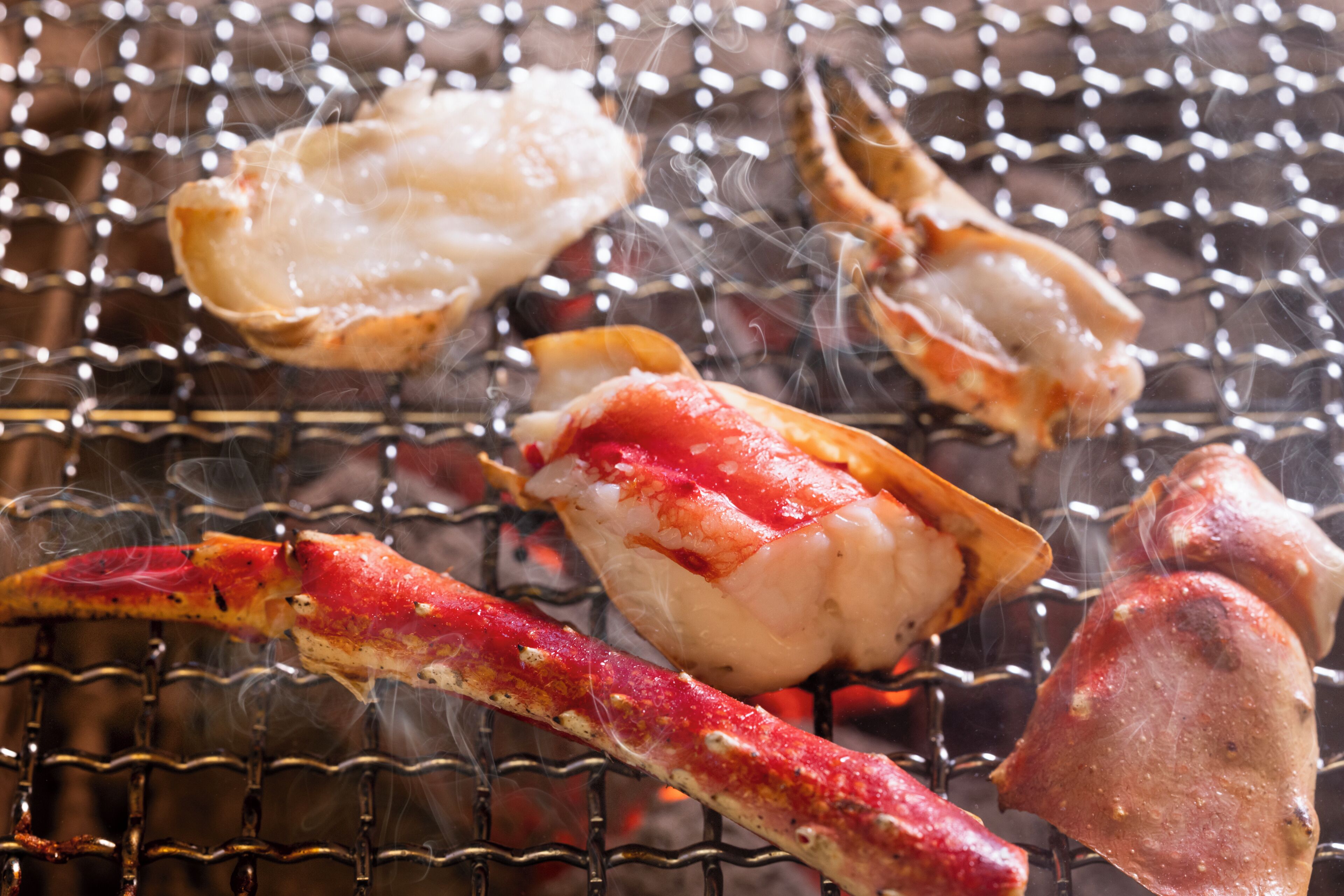 A grill with seafood, including lobster and crab, being cooked.