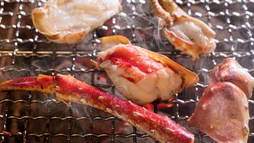 A grill with seafood, including lobster and crab, being cooked.