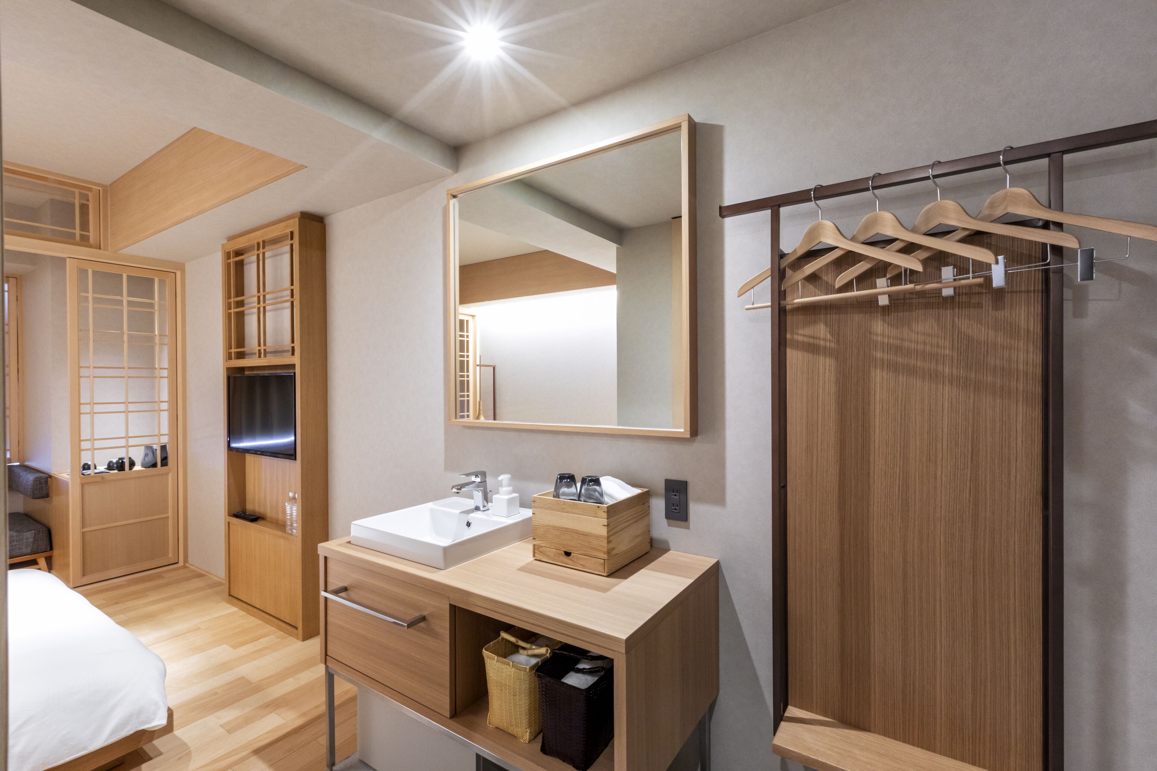 Un baño moderno con tocador de madera, un espejo grande y un perchero.