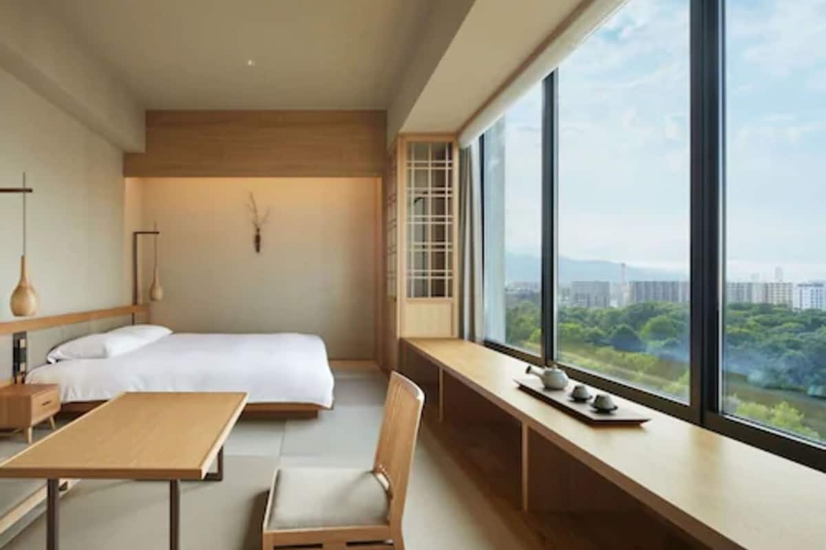 A modern bedroom with a large window, a bed, a desk, and a chair.