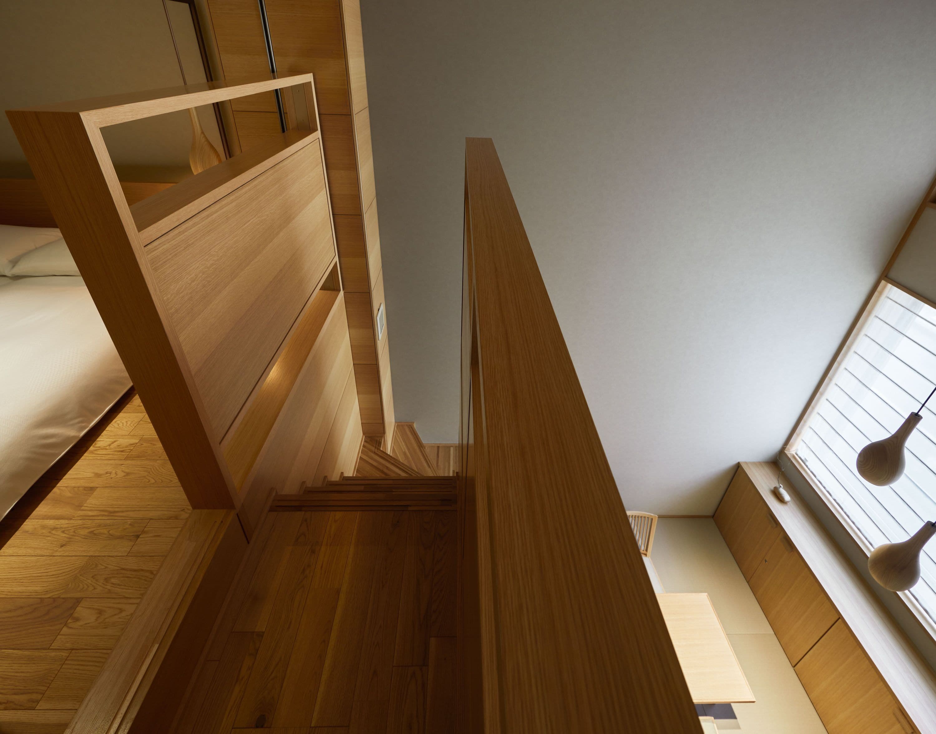 A compact, modern bedroom with a bunk bed, built-in shelving, and a sloped ceiling.