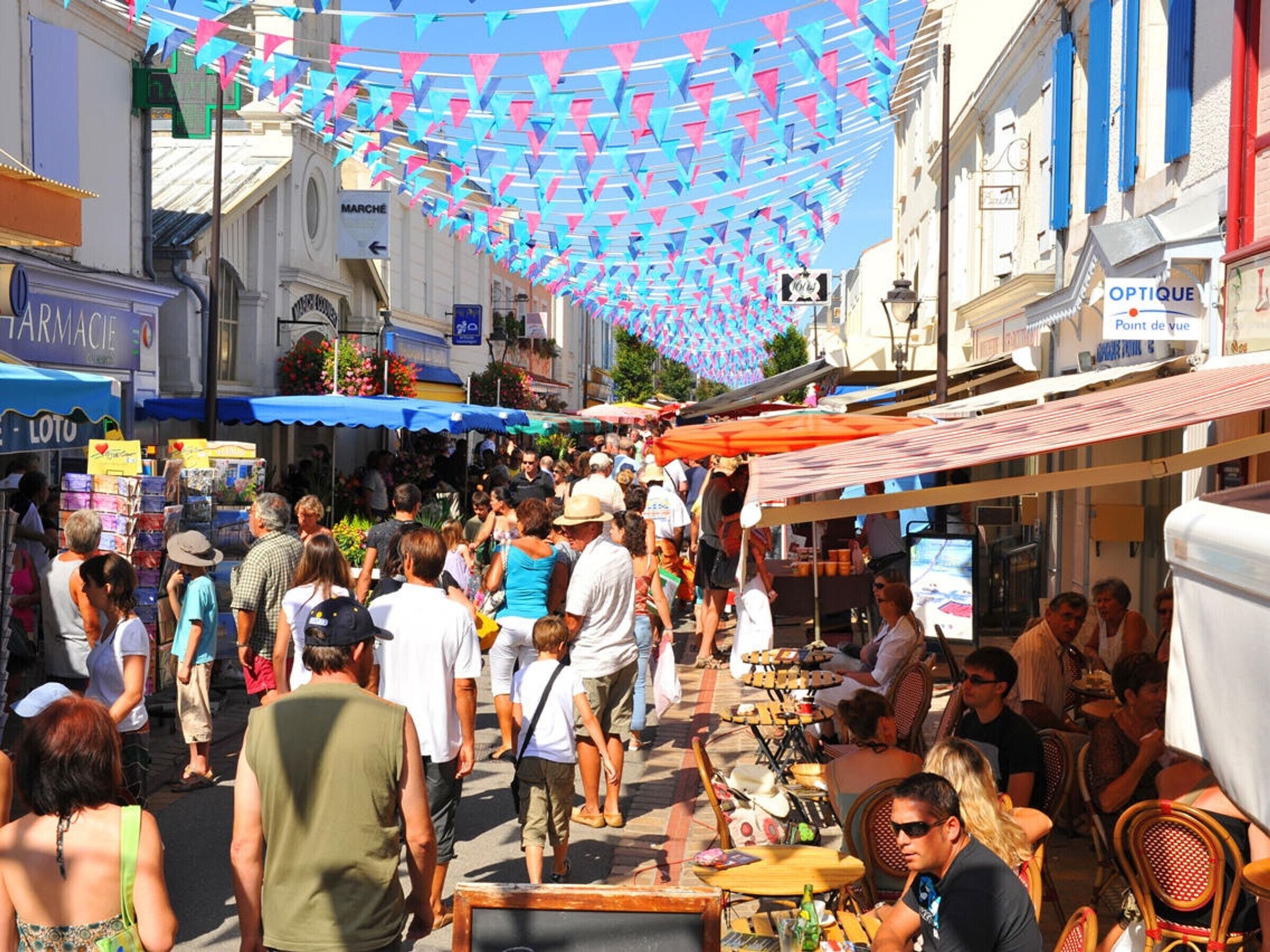 Una calle concurrida con mesas al aire libre y puestos de mercado.