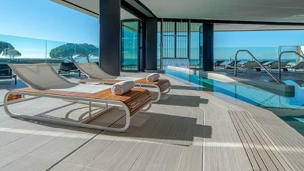 Un espace moderne aménagé au bord de la piscine, avec des chaises longues et une vue dégagée sur la mer.
