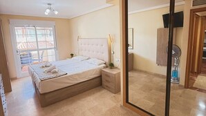 Een slaapkamer met een bed, nachtkastje en een schuifglazen deur naar een balkon.