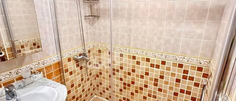 A bathroom with a glass-enclosed shower, a sink with a marble countertop, and a toilet.