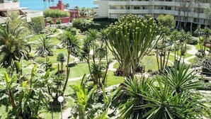 Un hotel con vistas al jardín, varios pisos y zona de piscina.