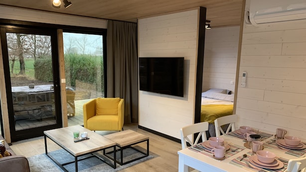 Une chambre moderne avec un canapé, une table à manger dressée pour deux personnes, une télévision et un lit.