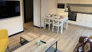 Une cuisine moderne avec des meubles blancs, un four encastré et un coin repas comprenant une table et des chaises.
