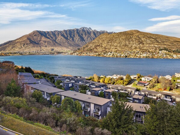 A residential area with modern houses, a lake, and mountains in the background.