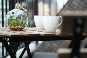 A clear glass terrarium with succulents on a wooden table, accompanied by two white cups with embossed patterns. - Shinsaibashi-House A (Osaka)