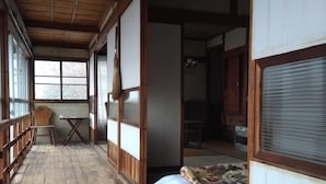 A traditional Japanese room with tatami flooring, a futon bed, sliding shoji doors, and a wooden ceiling. - Akiu Canada (Sendai)