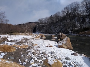 A river with snow-covered rocks and trees in the background. - Akiu Canada (Sendai)