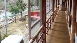 A covered corridor with wooden railings and large windows. - Akiu Canada (Sendai)