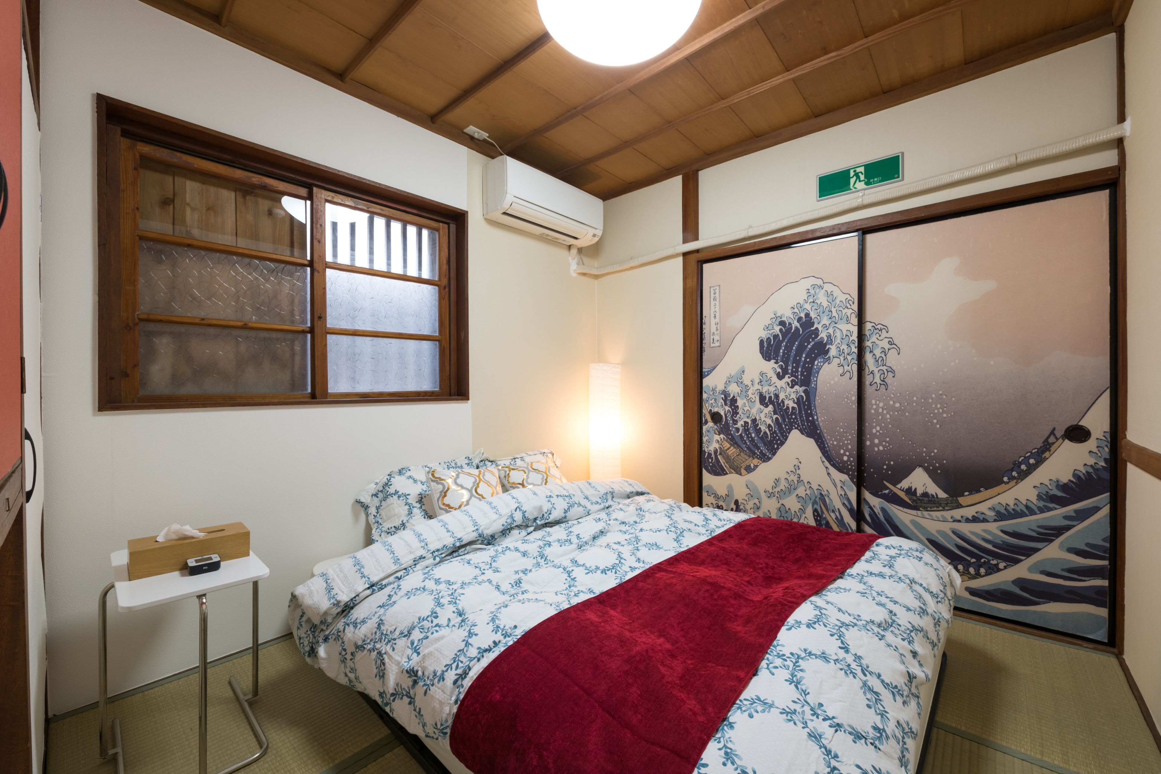 Een traditionele Japanse kamer met tatami vloeren, een futonbed, een shoji scherm en een wanddecoratie van een golf.