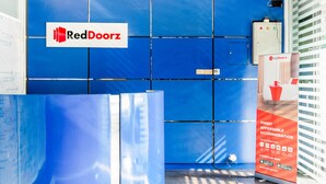 A RedDoorz sign on a blue tiled wall, a RedDoorz advertisement, and a control panel.