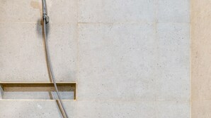 A showerhead attached to a tiled wall.