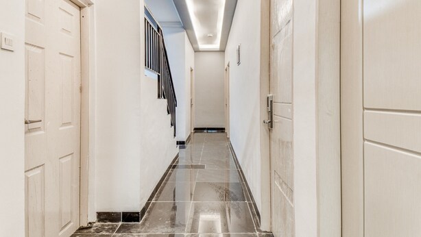 A hallway with a polished tile floor, white walls, and doors on both sides.